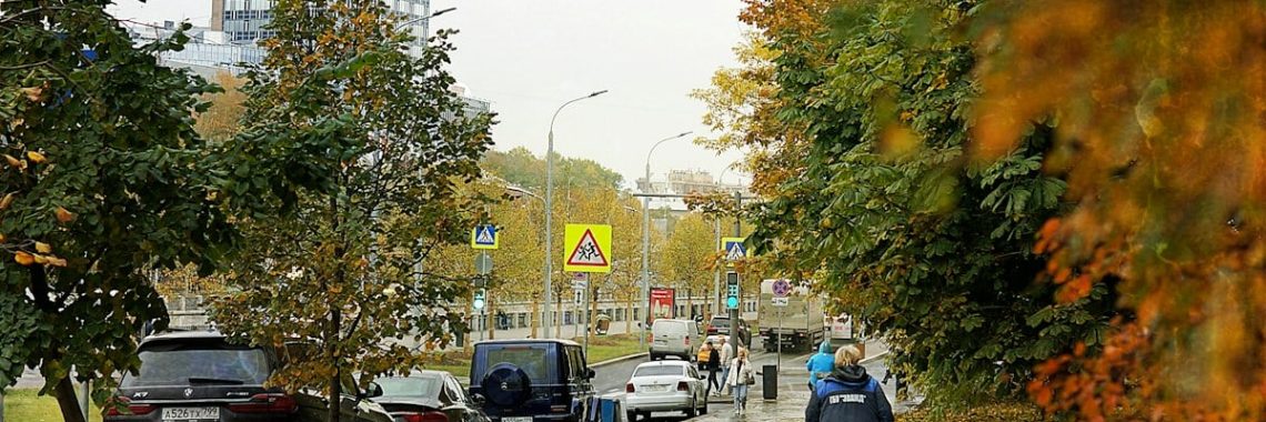 Autumn street with cars and a pedestrian