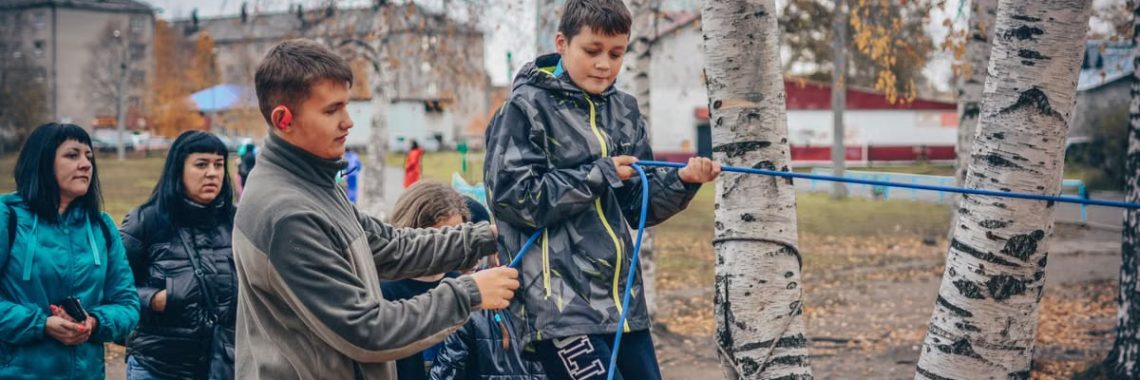Kids enjoying an outdoor rope activity among birch trees during fall.